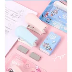 Dập ghim mini màu hồng và xanh pastel đặt trên vở học sinh