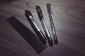 Các dụng cụ viết và bút xóa mặt cười trên bàn làm việc gỗ